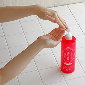 En person pumpar KIKU-MASAMUNE Sake Glossy Moist Skin Care Lotion i handen över vita kakelplattor.