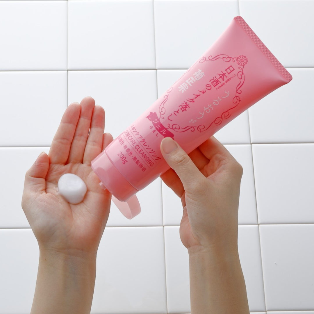 En person provar ut KIKU-MASAMUNE Sake Skin Care Cleansing Gel ur en rosa tub i handen framför vita kakelplattor.