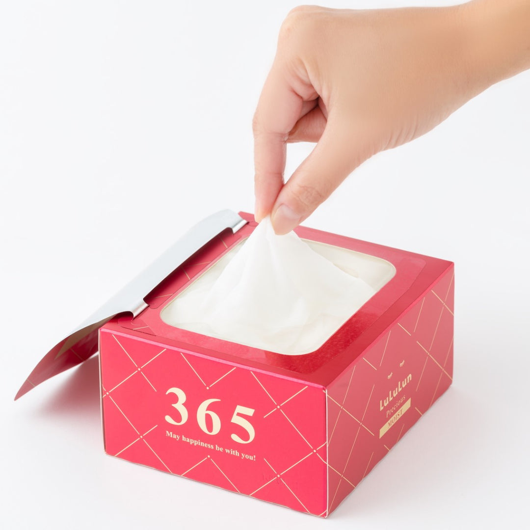 En hand drar ut en LuLuLun Precious Sheet Mask Red 32st ur en förpackning märkt 365 mot vit bakgrund.