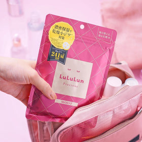 En hand packar ner LuLuLun Precious Sheet Mask Red 7st i en rosa necessär, arkmask för torr och mogen hud.