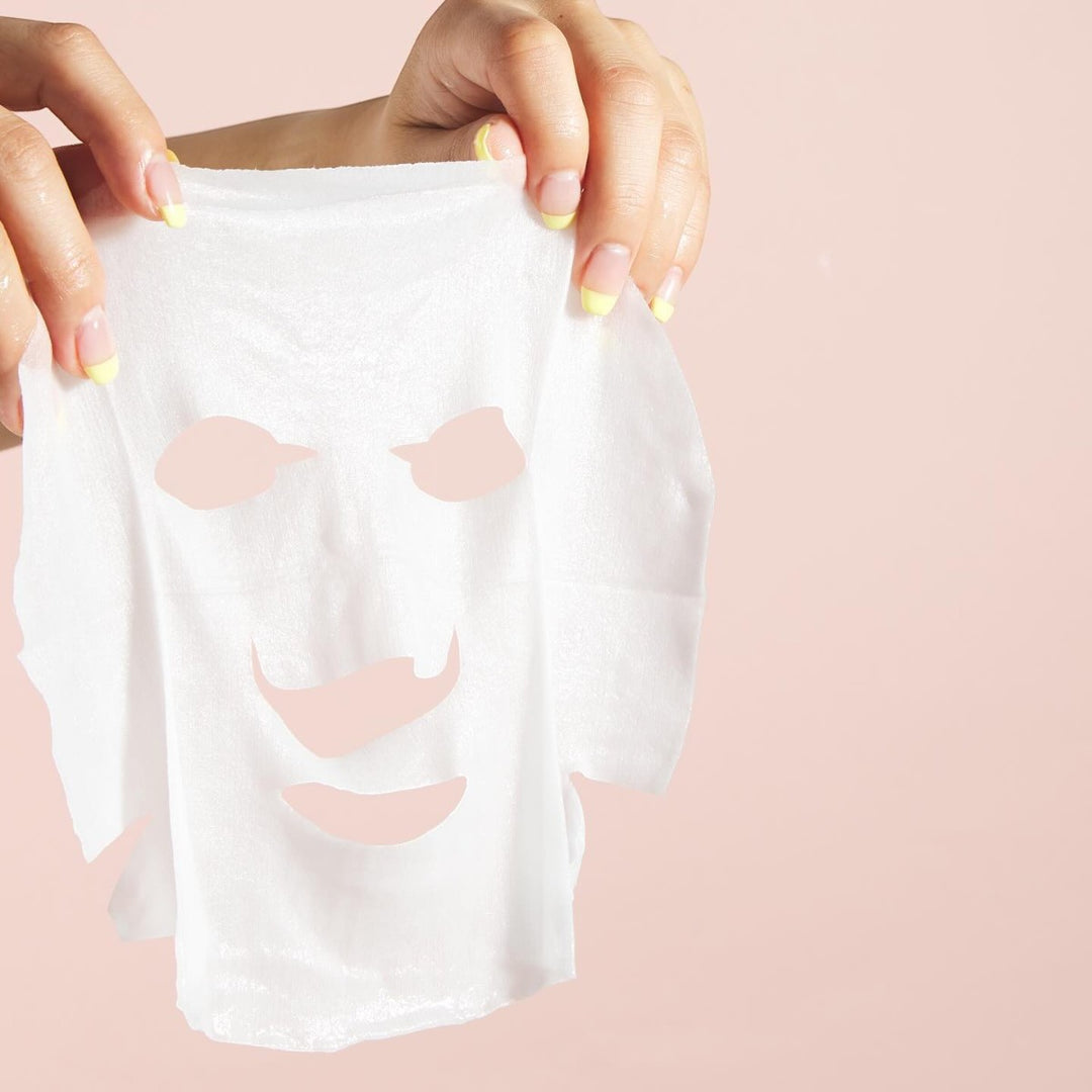 Två händer håller upp LuLuLun Premium Sheet Mask Yamanashi Peach 7st mot en ljusrosa bakgrund.