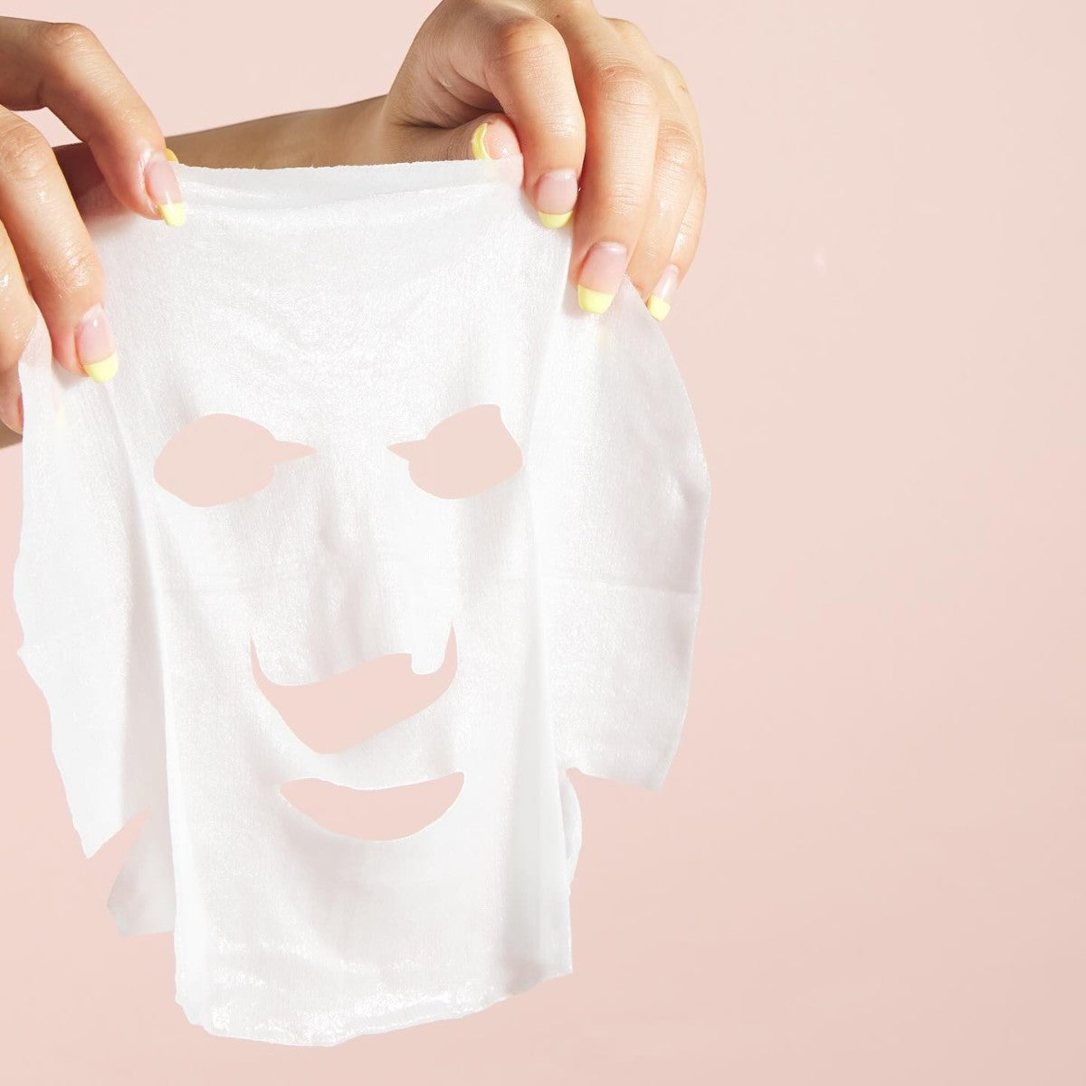 Två händer håller upp LuLuLun Premium Sheet Mask Yamanashi Peach 7st mot en ljusrosa bakgrund.