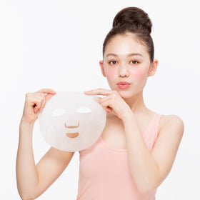 Kvinna håller i momopuri Moist Barrier Serum Mask BC-Niacinamide 10 inspireraderad av japansk hudvård mot vit bakgrund.